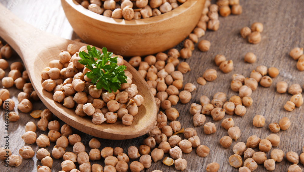 Bowl and spoon of chickpeas on wooden table Bowl and spoon of chickpeas on wooden table
