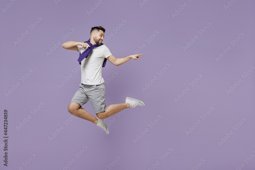 Full size body length smiling happy young brunet man 20s wear white t-shirt purple shirt jump pointing back on workspace area copy space mock up isolated on pastel violet background studio portrait