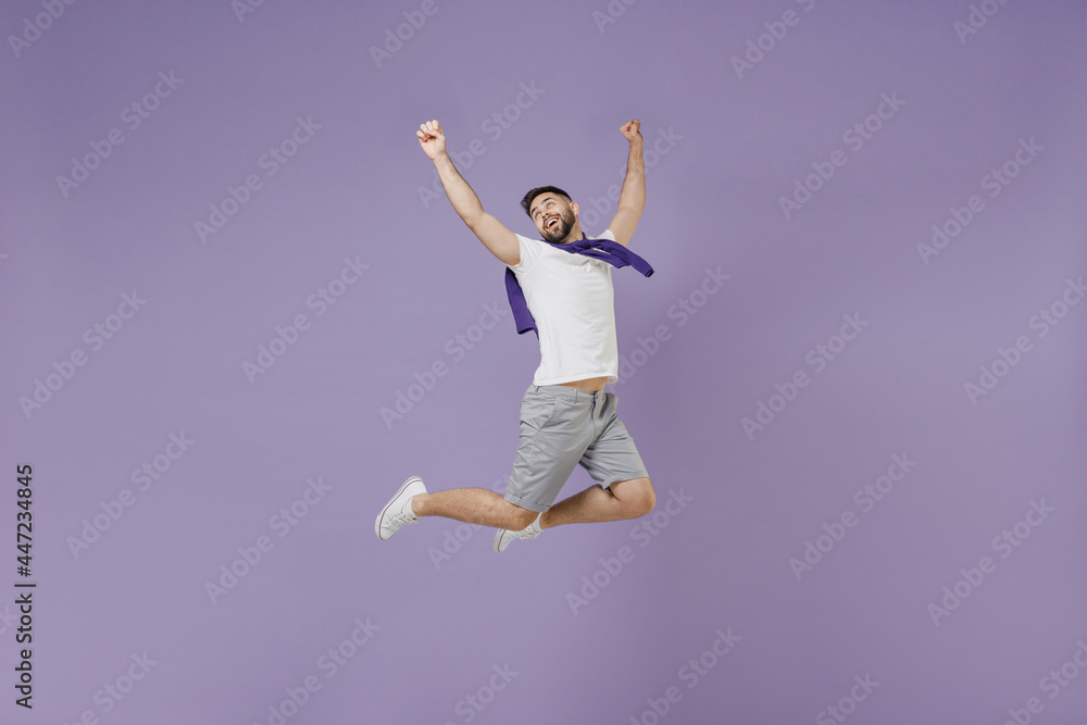Full size body length young brunet man 20s wear white t-shirt purple shirt jump celebrate clench fists say yes isolated on pastel violet background studio portrait. People emotions lifestyle concept.