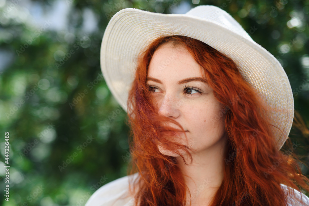 Close-up portrait of young woman with hat outdoors in city, headshot.