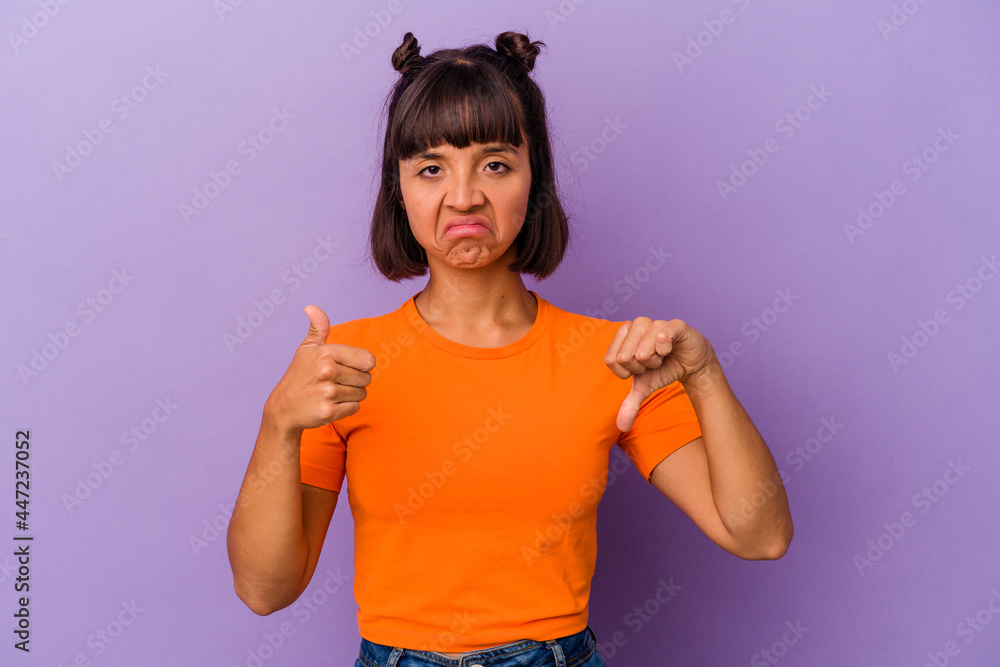 Young mixed race woman isolated on purple background showing thumbs up and thumbs down, difficult choose concept Young mixed race woman isolated on purple background showing thumbs up and thumbs down, difficult choose concept