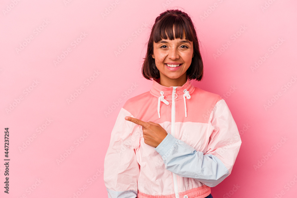 Young mixed race woman isolated on pink background smiling and pointing aside, showing something at blank space. Young mixed race woman isolated on pink background smiling and pointing aside, showing something at blank space.