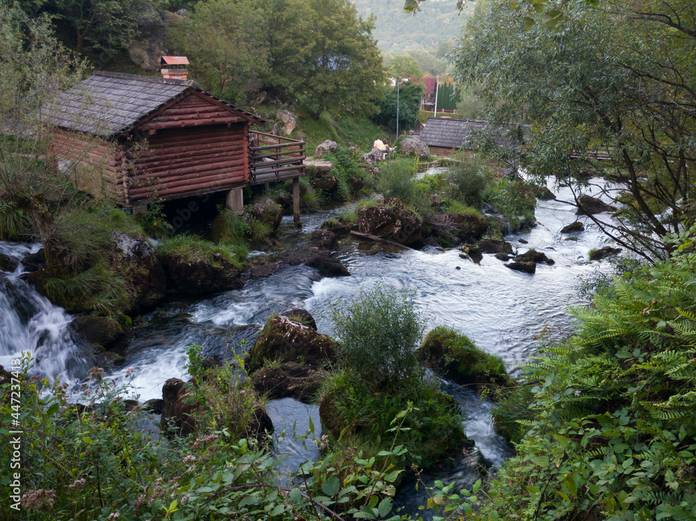 Rocks and cascades on wild stream Krupa and small wooden house on popular picnic place Krupa na Vrbasu near Banja Luka, Bosnia and Herzegovina