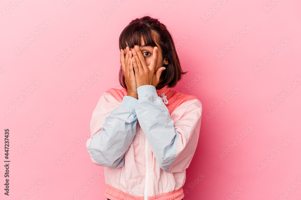 Young mixed race woman isolated on pink background blink through fingers frightened and nervous. Young mixed race woman isolated on pink background blink through fingers frightened and nervous.