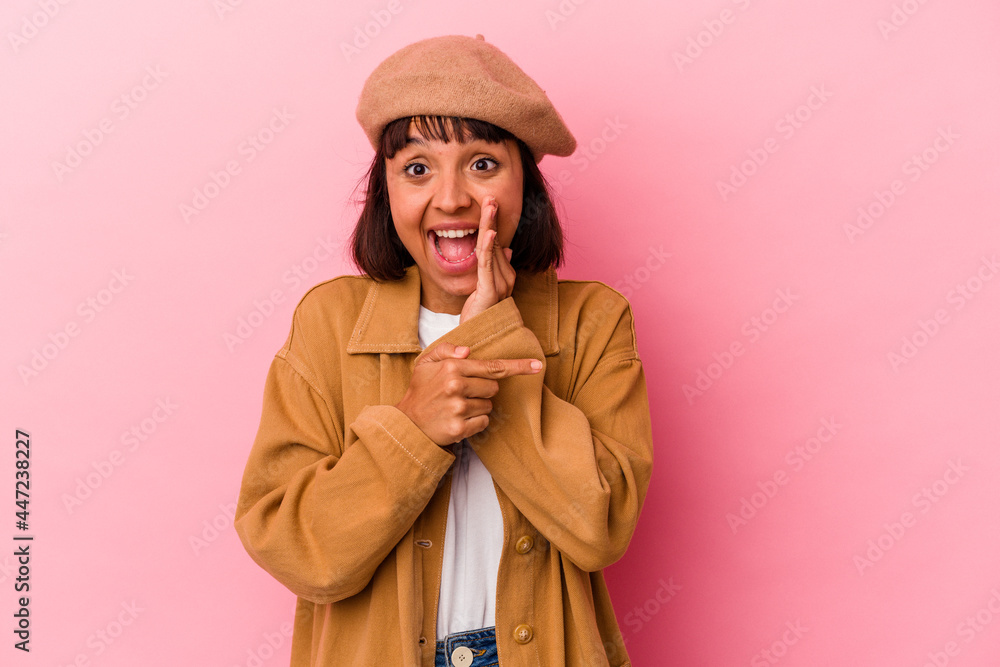 Young mixed race woman isolated on pink background saying a gossip, pointing to side reporting something. Young mixed race woman isolated on pink background saying a gossip, pointing to side reporting something.