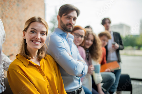 Portrait of young businesswoman with group of entrepreneurs indoors in office, looking at camera.