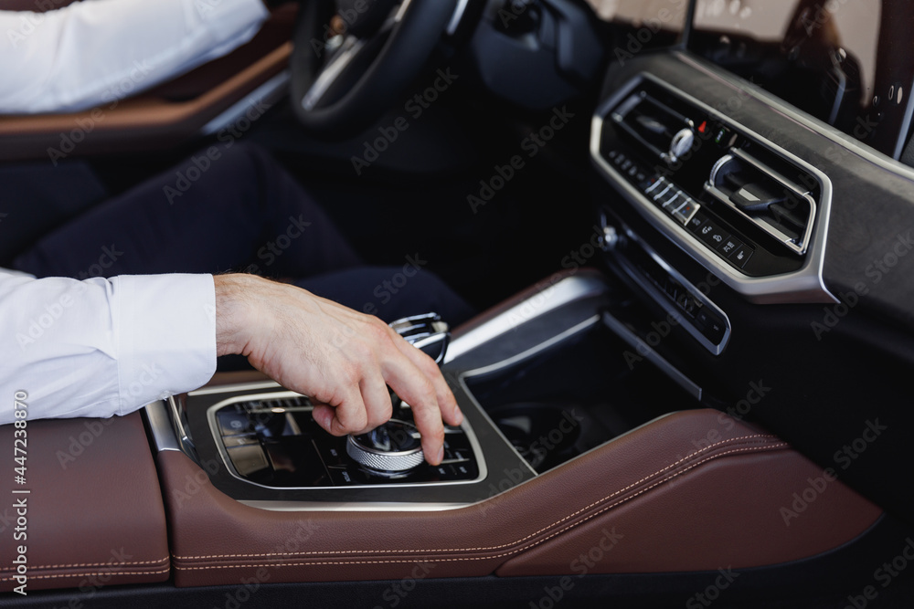 Close up cropped up photo shot hands european businessman man wearing white shirt sitting in car salon driving changes gears hold steering wheel automobile modern vehicle. Car sales driver concept