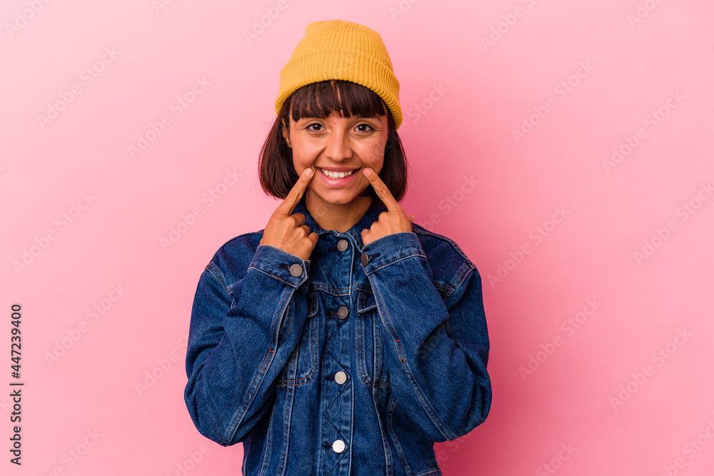 Young mixed race woman isolated on pink background smiles, pointing fingers at mouth. Young mixed race woman isolated on pink background smiles, pointing fingers at mouth.