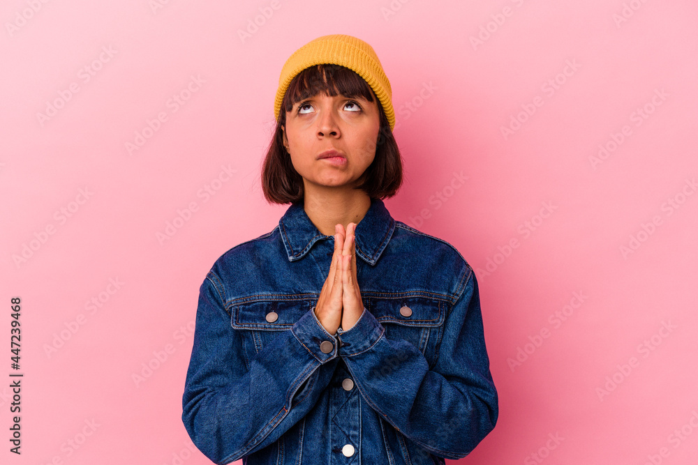 Young mixed race woman isolated on pink background holding hands in pray near mouth, feels confident. Young mixed race woman isolated on pink background holding hands in pray near mouth, feels confident.