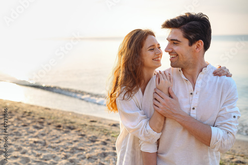 Romantic happy young couple two friends family man woman 20s wear casual clothes hug each other going to kiss at sunrise over sea sand beach ocean outdoor exotic seaside in summer day sunset evening.