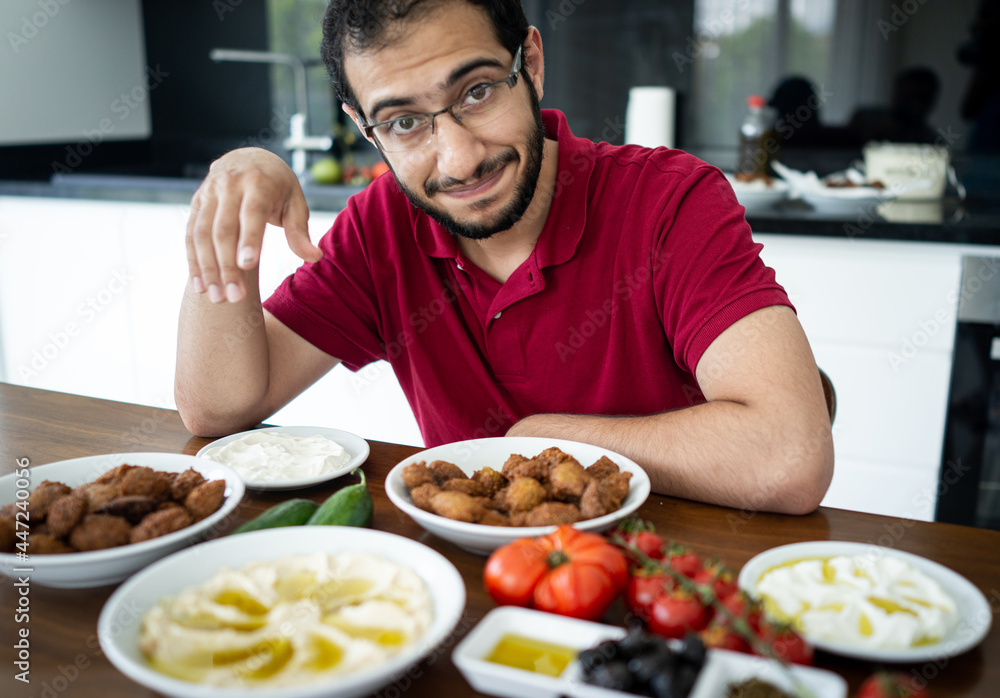Middle Eastern young man sitting and eating traditional food alone