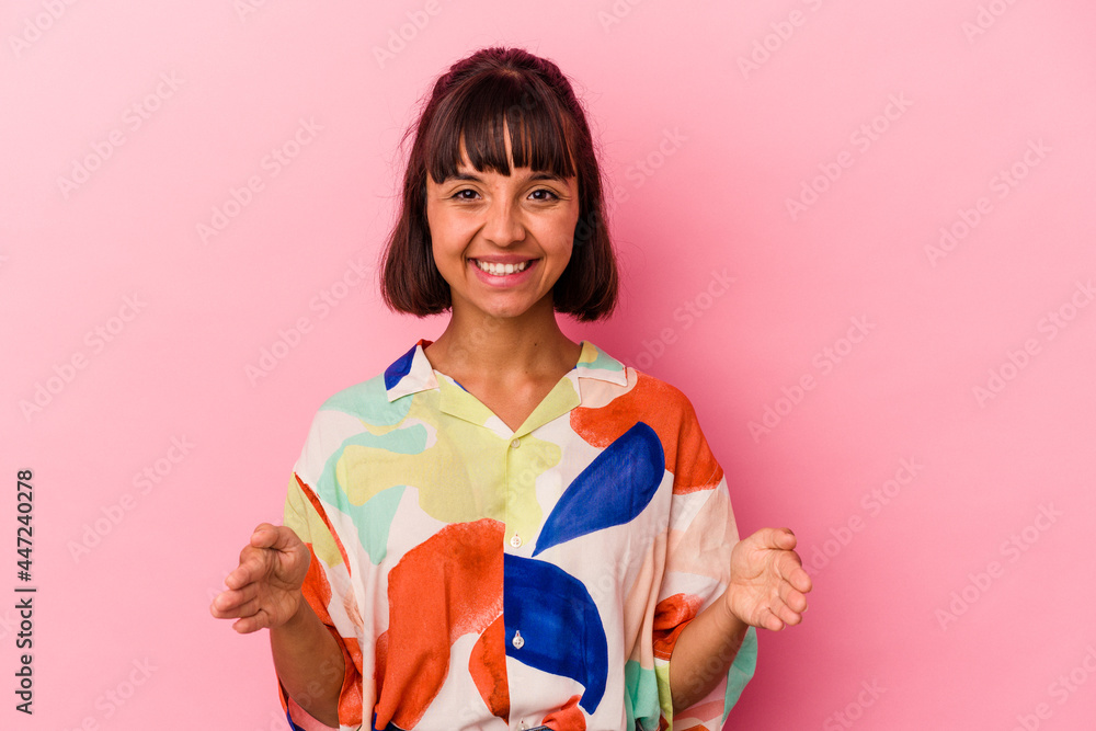 Young mixed race woman isolated on pink background holding something with both hands, product presentation. Young mixed race woman isolated on pink background holding something with both hands, product presentation.