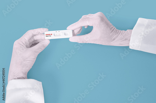 Scientist hands showing rapid laboratory COVID-19 test for diagnosis Positive test result for the new rapidly spreading Coronavirus Covid-19 on blue background Pandemic infectious concept