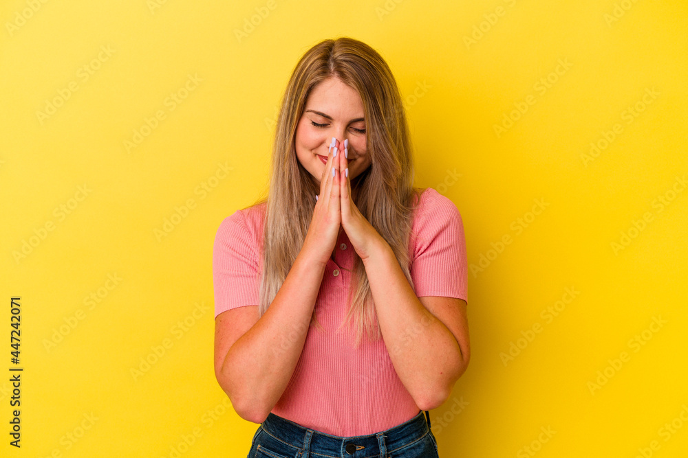 Young russian woman isolated on yellow background holding hands in pray near mouth, feels confident. Young russian woman isolated on yellow background holding hands in pray near mouth, feels confident.