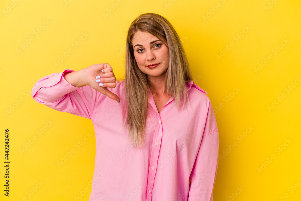Young russian woman isolated on yellow background showing thumb down, disappointment concept. Young russian woman isolated on yellow background showing thumb down, disappointment concept.