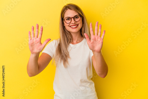 Young russian woman isolated on yellow background showing number ten with hands.