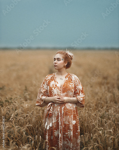 a young woman stands among a wheat field