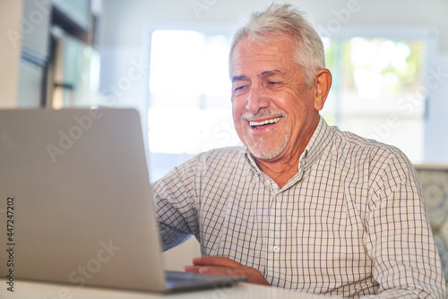 Laughing senior is happy about a video call at home