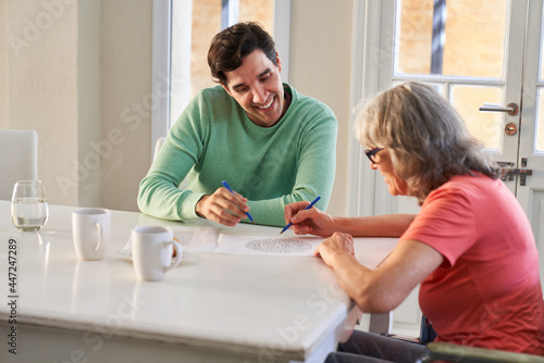 Young man and elderly woman with dementia solving maze puzzles
