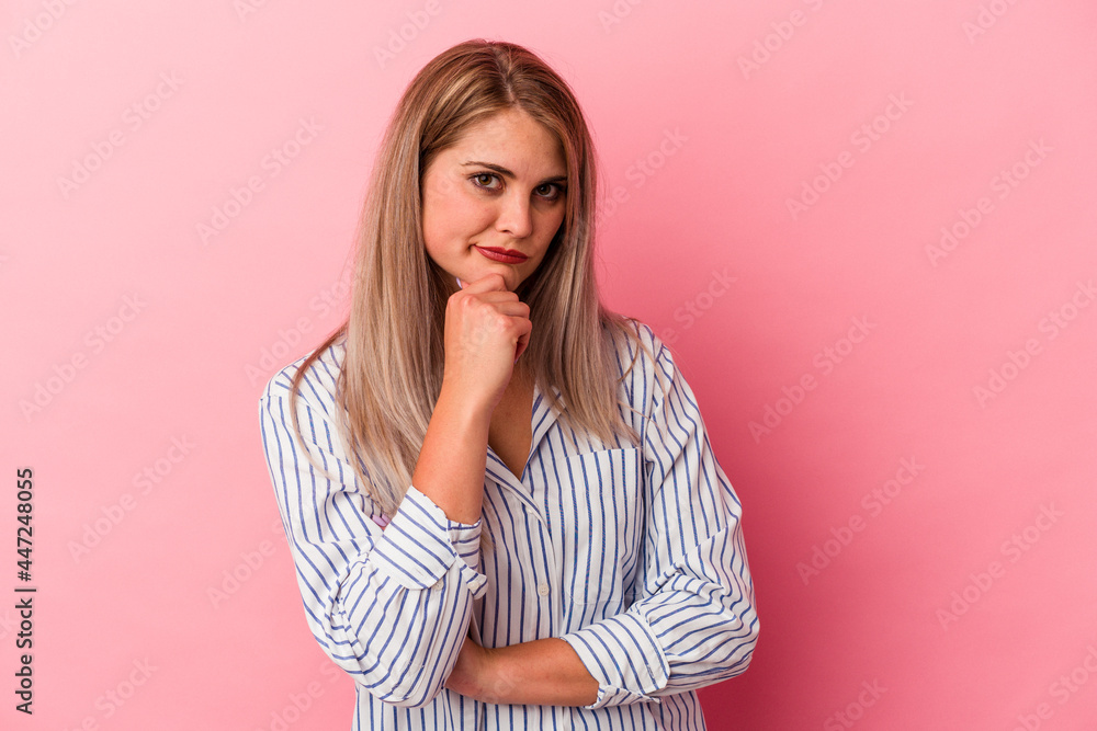 Young russian woman isolated on pink background suspicious, uncertain, examining you. Young russian woman isolated on pink background suspicious, uncertain, examining you.