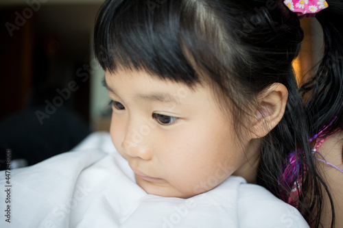 Thoughtful asian little girl on bed with natural light from window