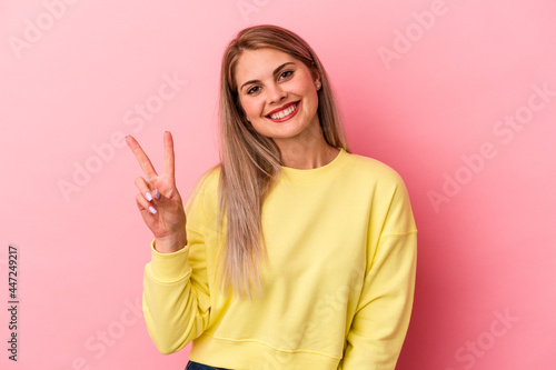Young russian woman isolated on pink background joyful and carefree showing a peace symbol with fingers.