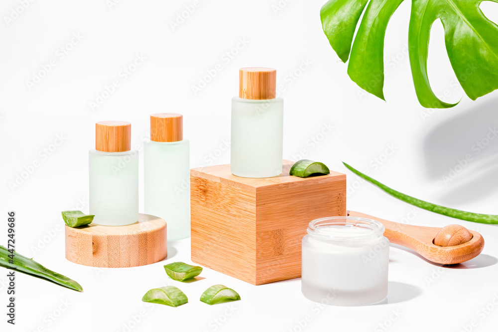 Natural cosmetics with aloe vera on wooden podiums in reusable bottles Natural cosmetics with aloe vera on wooden podiums in reusable bottles