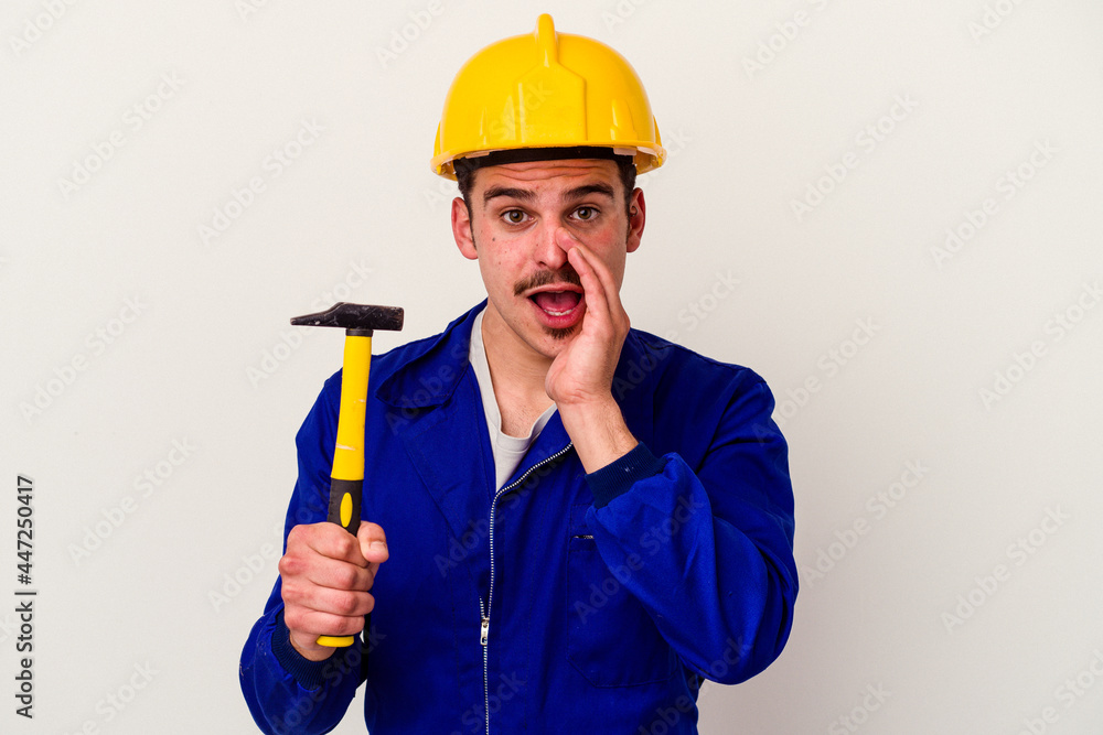 Young caucasian worker man holding a hammer isolated on white background is saying a secret hot braking news and looking aside Young caucasian worker man holding a hammer isolated on white background is saying a secret hot braking news and looking aside
