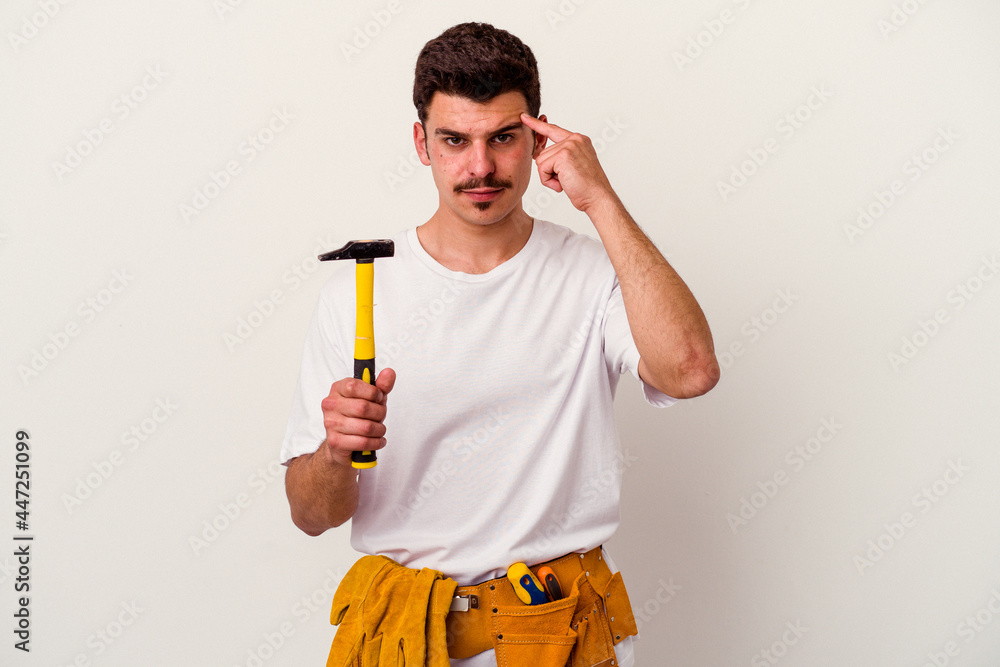 Young caucasian worker man with tools isolated on white background pointing temple with finger, thinking, focused on a task. Young caucasian worker man with tools isolated on white background pointing temple with finger, thinking, focused on a task.