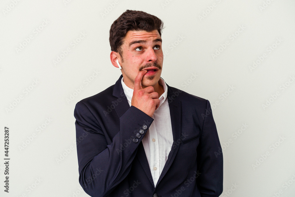 Young business caucasian man wearing wireless headphones isolated on white background relaxed thinking about something looking at a copy space. Young business caucasian man wearing wireless headphones isolated on white background relaxed thinking about something looking at a copy space.