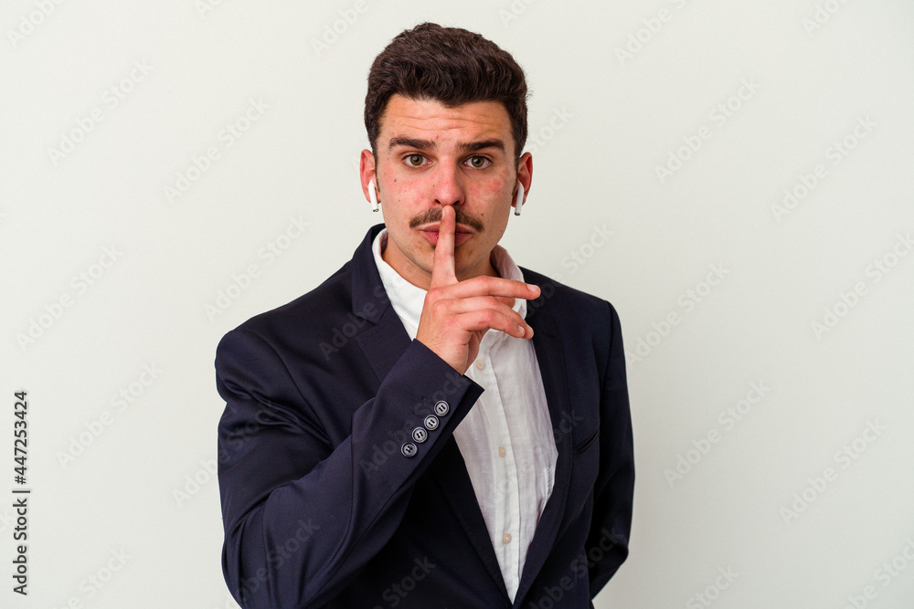 Young business caucasian man wearing wireless headphones isolated on white background keeping a secret or asking for silence. Young business caucasian man wearing wireless headphones isolated on white background keeping a secret or asking for silence.