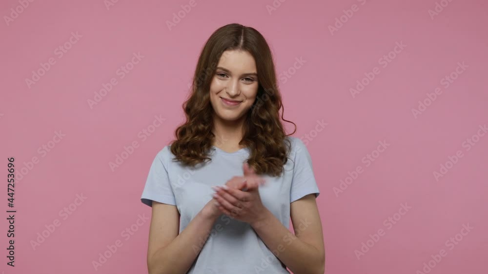 Cheerful dark haired young woman in blue casual style T-shirt applauding, clapping hands congratulating you with victory, smiling happily. Indoor studio shot isolated over pink background. Cheerful dark haired young woman in blue casual style T-shirt applauding, clapping hands congratulating you with victory, smiling happily. Indoor studio shot isolated over pink background.