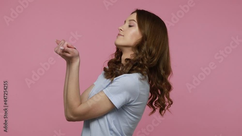 Beautiful young woman in casual blue T-shirt touching her head and showing explosion, enjoying beauty procedures, self care. Indoor studio shot isolated over pink background. photo