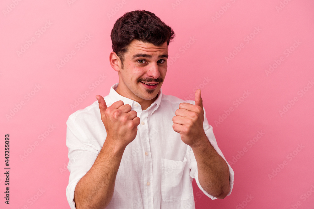 Young caucasian man isolated on pink background raising both thumbs up, smiling and confident. Young caucasian man isolated on pink background raising both thumbs up, smiling and confident.