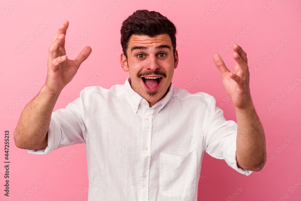 Fototapeta premium Young caucasian man isolated on pink background receiving a pleasant surprise, excited and raising hands.