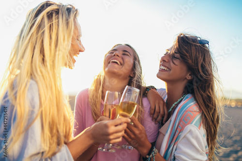 Photography Happy young women drinking champagne at bachelorette party on the beach