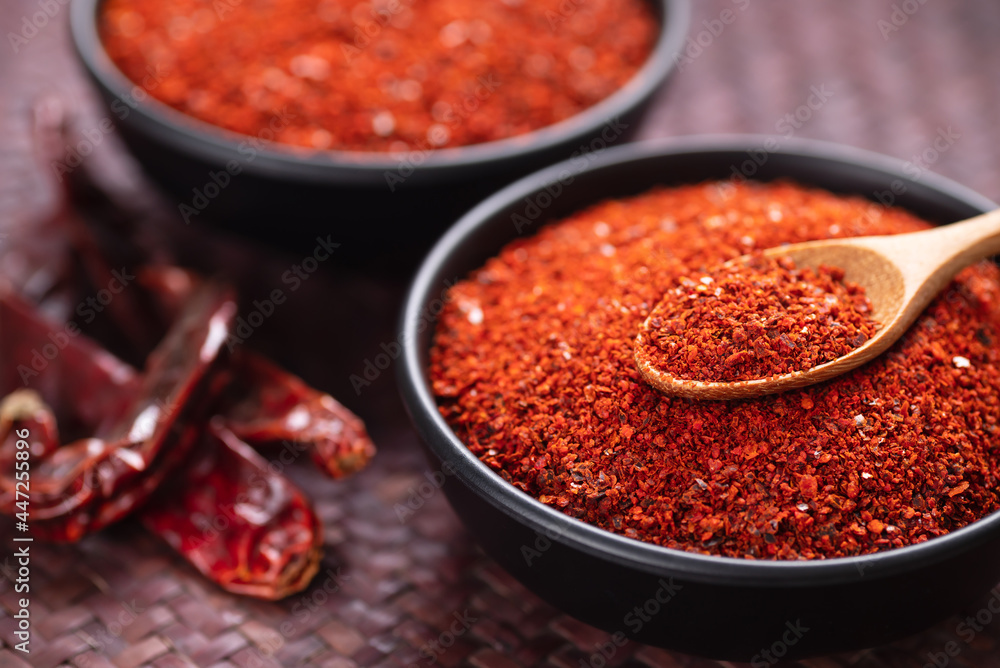 Red chili pepper powder in a bowl with spoon, Chili flakes Red chili pepper powder in a bowl with spoon, Chili flakes