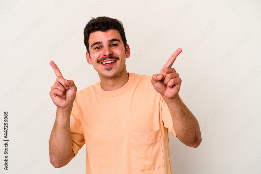 Young caucasian man isolated on white background pointing to different copy spaces, choosing one of them, showing with finger. Young caucasian man isolated on white background pointing to different copy spaces, choosing one of them, showing with finger.