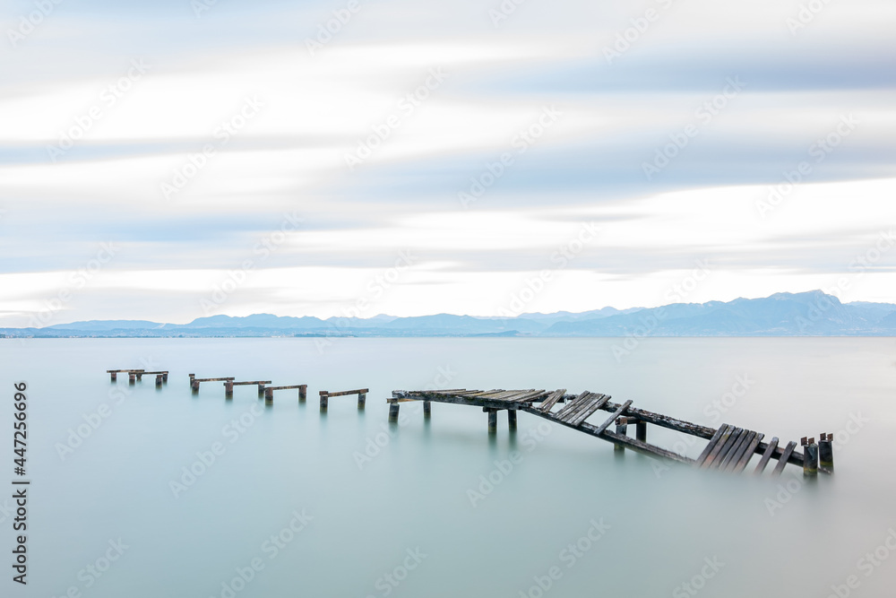 Abandoned wooden pier in lake during sunrise, long exposure