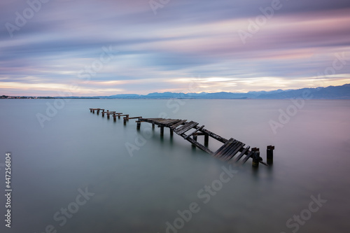 Abandoned wooden pier in lake during sunrise, long exposure