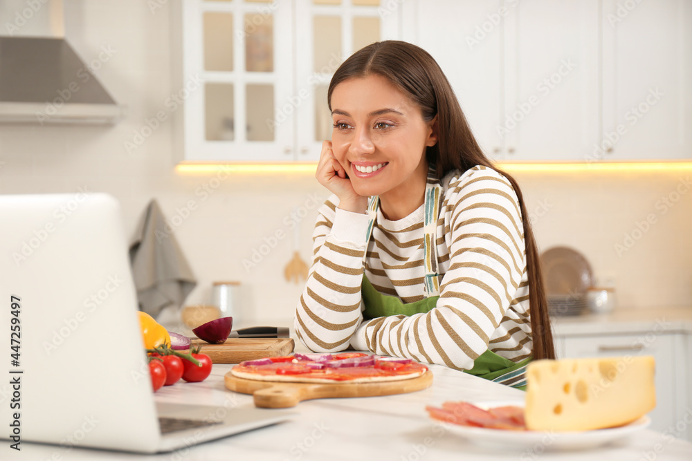 Happy woman watching online cooking course via laptop in kitchen Happy woman watching online cooking course via laptop in kitchen
