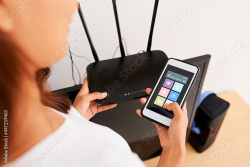Obraz na plátne Hands of woman connecting smart home application on her phone to wi-fi router