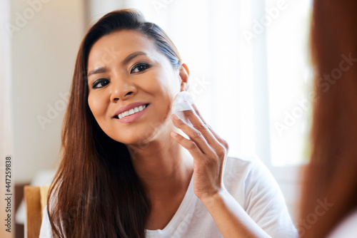 Happy beautiful young woman applying powder on her face to set make-up