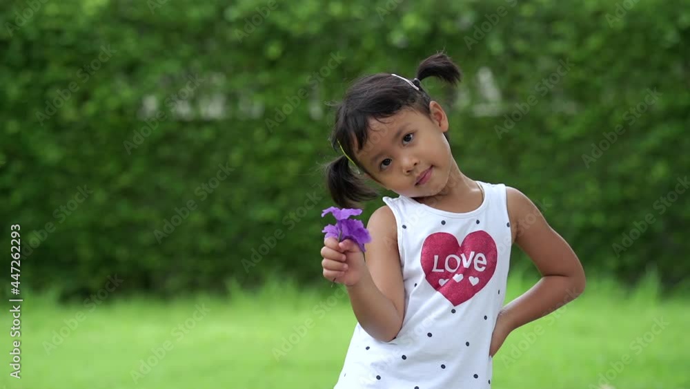 Adorable Asian small girl holding violet flowers at garden. Adorable Asian small girl holding violet flowers at garden.