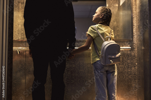 Canvastavla Rear view on unrecognizable man with child standing in lift, kidnapping children concept