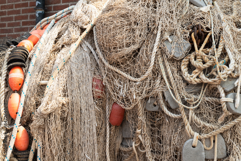 Different fishing nets hang to dry against the wall on the quay.