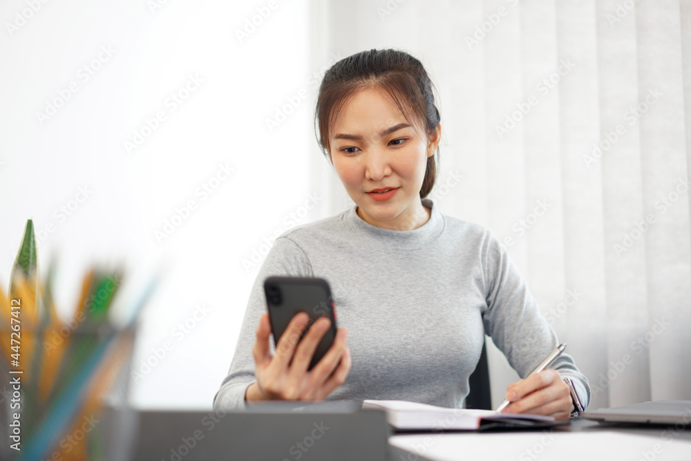 Office work concept a female officer using a mobile phone to check meeting agenda for tomorrow Office work concept a female officer using a mobile phone to check meeting agenda for tomorrow