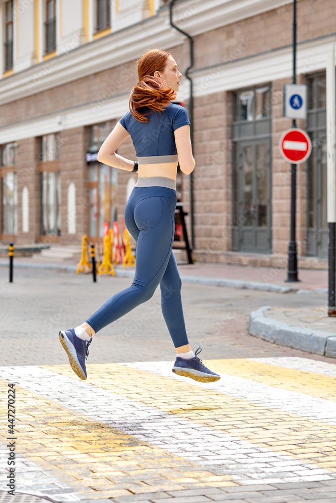 Runner athlete running in town. woman fitness jogging workout wellness concept. Redhead caucasian lady in sportswear concentrated on sport, side view portrait. sport, fitness concept Runner athlete running in town. woman fitness jogging workout wellness concept. Redhead caucasian lady in sportswear concentrated on sport, side view portrait. sport, fitness concept