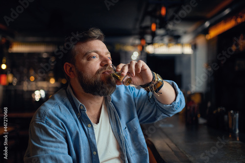 Bearded man drinks alcohol beverage in bar