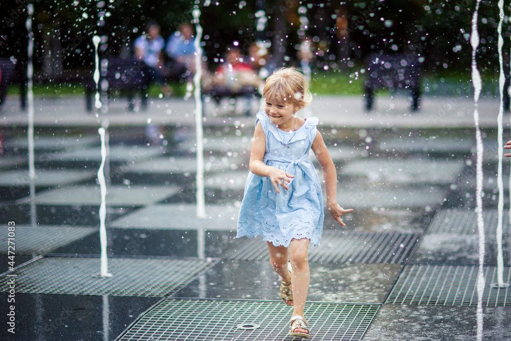 Naklejka premium happy little girl running under splashing water